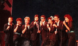 One of the various a cappella vocal groups I've been a member of in L.A., Eight To The Bar. This would have been shortly after my stint in the L.A. Jazz Choir, and several of these singers besides myself were indeed veterans of LAJC. This is us on stage at an At My Place gig in Santa Monica, circa 1985. Personnel, L to R: Stewart Wilson-Turner, Jan Roper, Barbara Bentree, Randy Crenshaw, Bill New, Pam Austin, Gary Rosen, Robin Ehlers. Note the extreme mic-holding hand precision!
